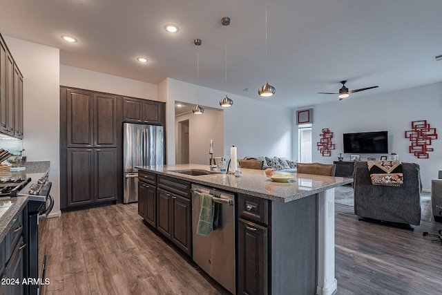 kitchen with sink, an island with sink, stainless steel appliances, dark brown cabinetry, and dark wood-type flooring