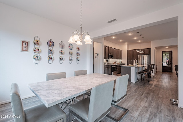 dining room with sink, an inviting chandelier, and hardwood / wood-style floors