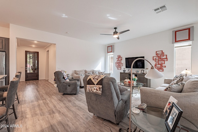 living room featuring crown molding, light wood-type flooring, and ceiling fan