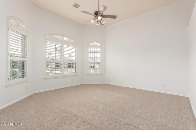spare room featuring ceiling fan, visible vents, plenty of natural light, and carpet