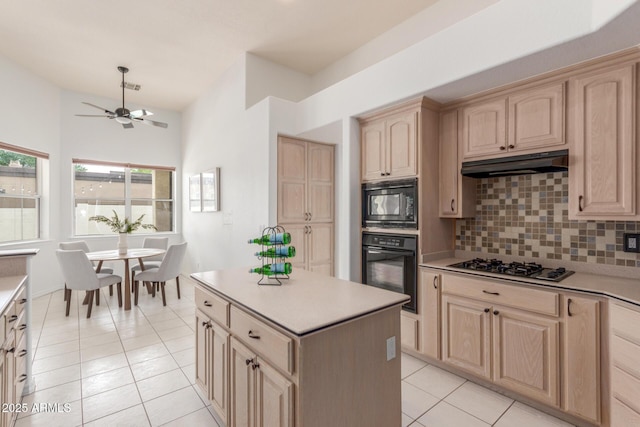 kitchen featuring light brown cabinets, decorative backsplash, black appliances, and under cabinet range hood