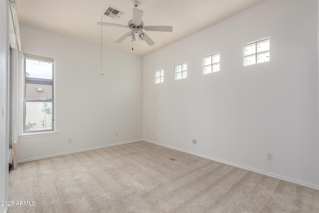 empty room featuring visible vents, a ceiling fan, baseboards, and light carpet