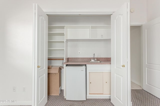 bar featuring a sink, light tile patterned floors, indoor wet bar, and dishwasher