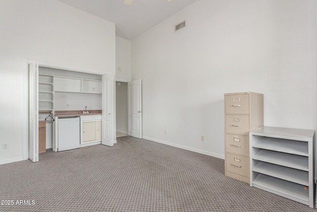unfurnished bedroom with a sink, carpet floors, high vaulted ceiling, and visible vents