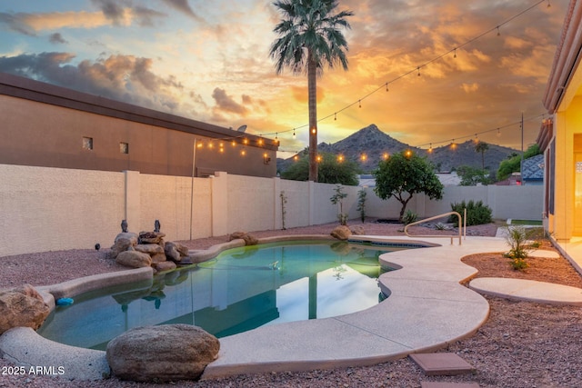 pool at dusk featuring a fenced in pool, a fenced backyard, and a patio