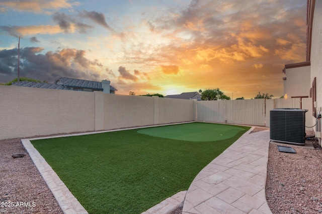 yard at dusk with central air condition unit, a fenced backyard, and a patio area