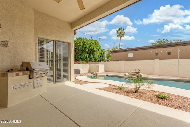view of pool with ceiling fan, a patio, a fenced backyard, area for grilling, and exterior kitchen