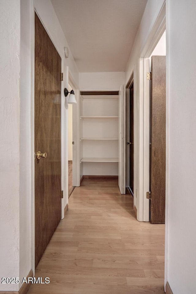 hall with light wood-type flooring and baseboards