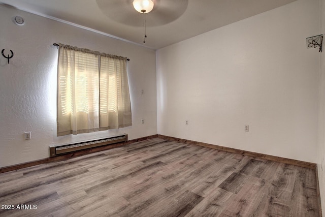 unfurnished room with a ceiling fan, baseboards, baseboard heating, and wood finished floors