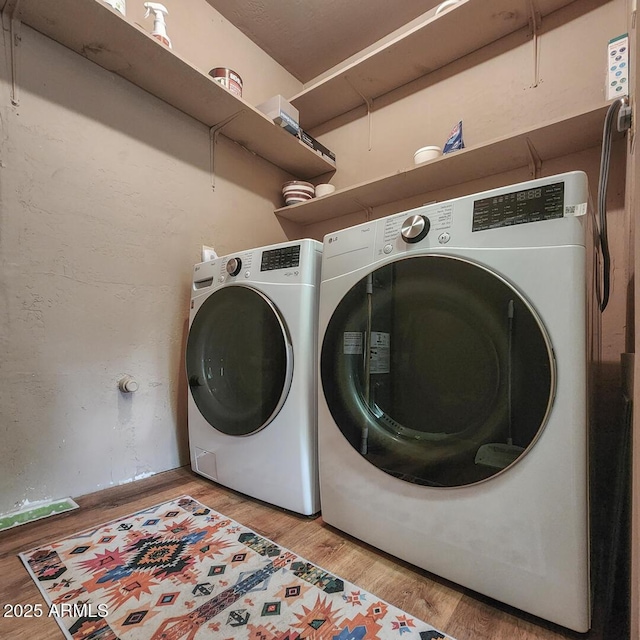 laundry area with laundry area, independent washer and dryer, and light wood-style flooring