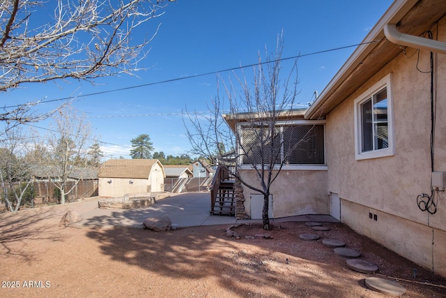 view of yard with a storage unit, a patio area, fence, an outdoor structure, and stairs