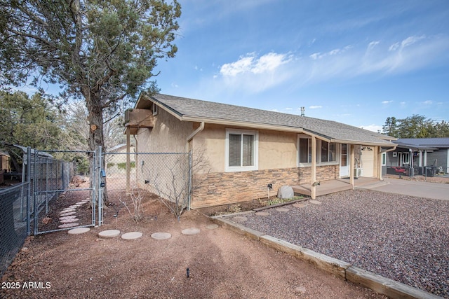 ranch-style home with a garage, fence, stone siding, a gate, and stucco siding