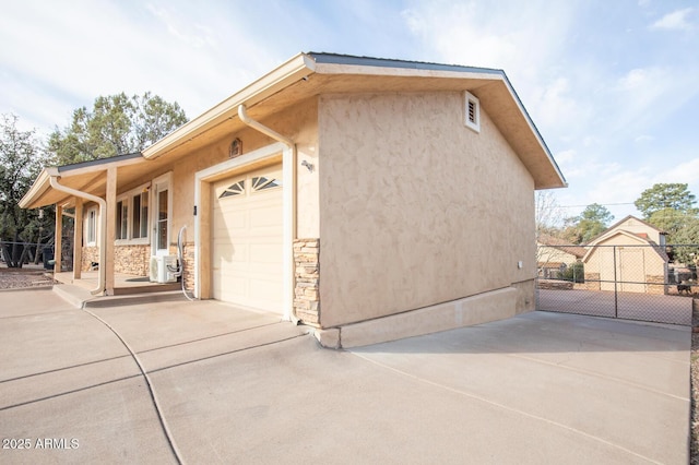 view of home's exterior with a garage, stone siding, driveway, and stucco siding