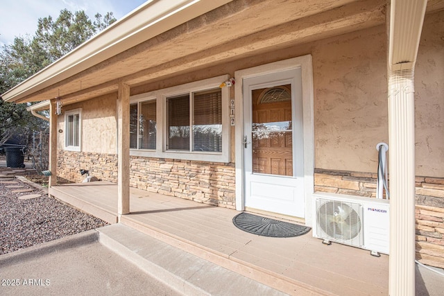 entrance to property featuring ac unit, stone siding, and stucco siding