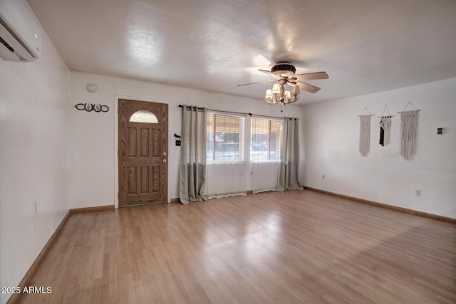 foyer entrance featuring light wood-type flooring, a wall mounted air conditioner, and baseboards