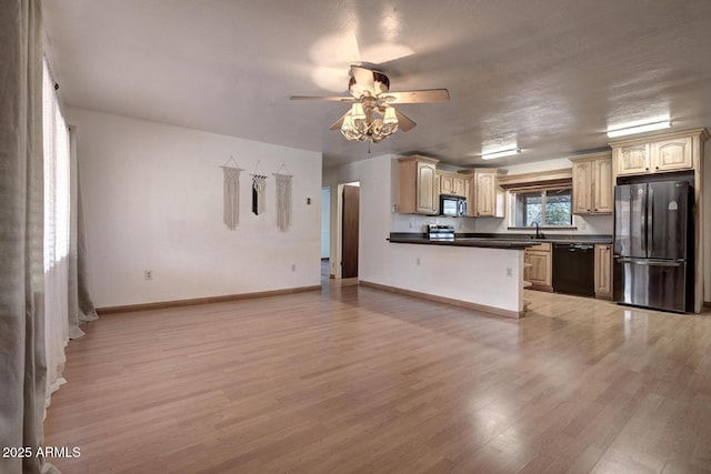 kitchen featuring dark countertops, black appliances, light wood-type flooring, and a sink