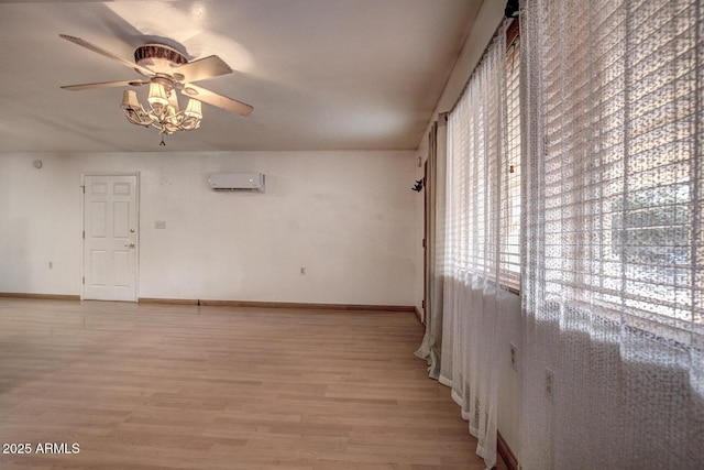 spare room with light wood-type flooring, ceiling fan, baseboards, and a wall mounted AC