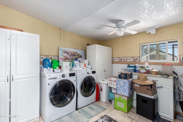 clothes washing area with ceiling fan, washer and clothes dryer, cabinets, and a textured ceiling