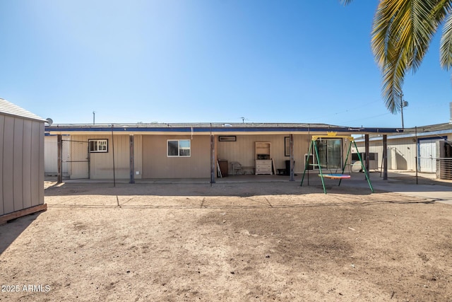 rear view of property featuring a trampoline and a patio area