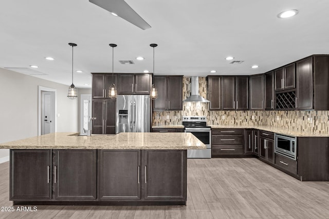 4602 W Monte Cristo Ave, Glendale, AZ 85306 - kitchen with appliances with stainless steel finishes, wall chimney exhaust hood, dark brown cabinets, decorative backsplash, and light wood-style flooring