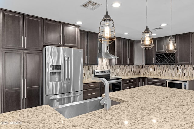 4602 W Monte Cristo Ave, Glendale, AZ 85306 - kitchen with appliances with stainless steel finishes, dark brown cabinets, light stone counters, wall chimney range hood, and backsplash