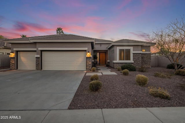 prairie-style home featuring a garage, stone siding, driveway, and stucco siding