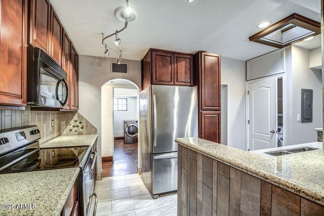 2534 N 52nd St, Phoenix, AZ 85008 - kitchen featuring arched walkways, washer / dryer, stainless steel appliances, backsplash, and light stone countertops