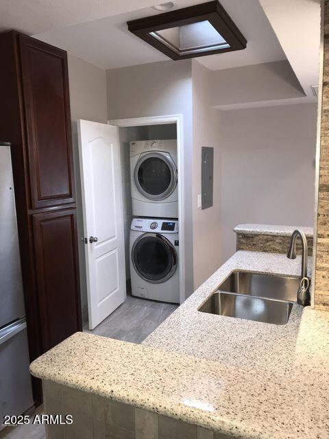 2534 N 52nd St, Phoenix, AZ 85008 - washroom featuring light wood finished floors, electric panel, a sink, stacked washer / dryer, and laundry area
