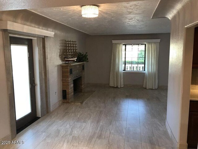 2534 N 52nd St, Phoenix, AZ 85008 - unfurnished living room with a brick fireplace, a textured ceiling, and light wood-style floors