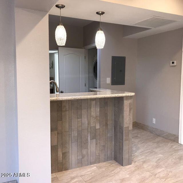 2534 N 52nd St, Phoenix, AZ 85008 - kitchen with light countertops, hanging light fixtures, electric panel, and stacked washer / dryer
