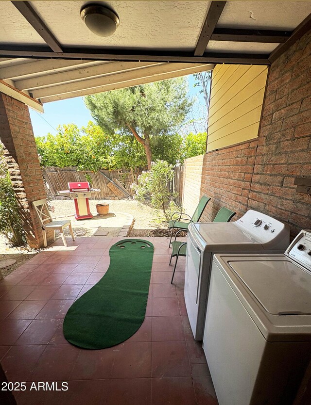 2534 N 52nd St, Phoenix, AZ 85008 - laundry area with tile patterned floors, washer and clothes dryer, laundry area, a healthy amount of sunlight, and brick wall