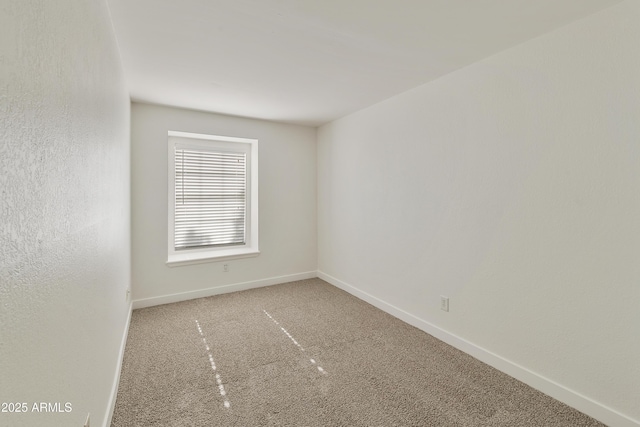 empty room featuring baseboards and carpet flooring