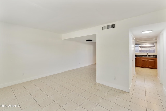 unfurnished room featuring baseboards, visible vents, light tile patterned floors, and a sink