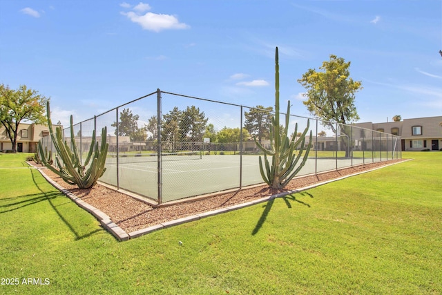 view of tennis court featuring fence and a lawn