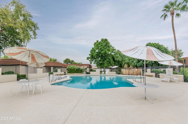 community pool with a patio and fence