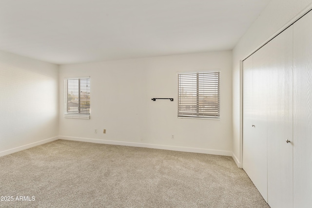 unfurnished bedroom with a closet, light carpet, and baseboards