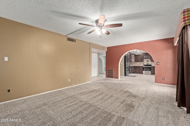 unfurnished living room with ceiling fan, a textured ceiling, and light carpet