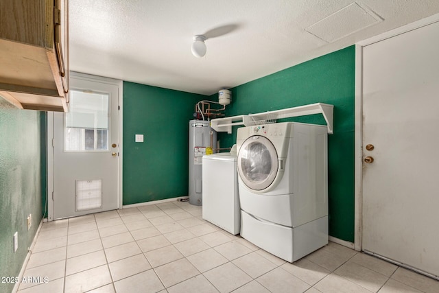 clothes washing area with washer and clothes dryer, a textured ceiling, light tile patterned floors, and water heater