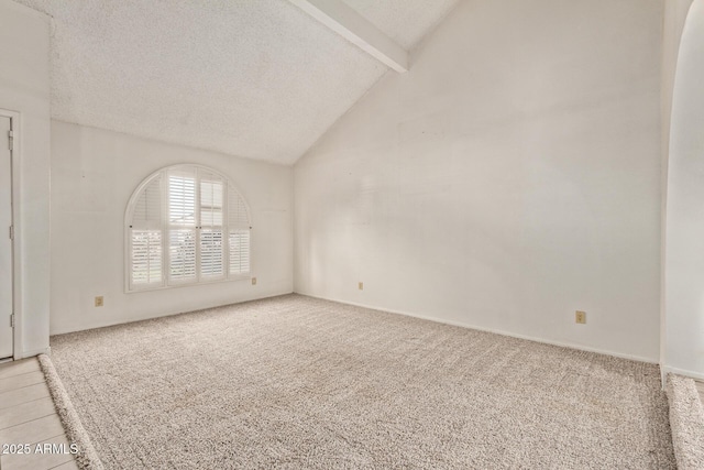 empty room with light carpet, vaulted ceiling with beams, and a textured ceiling