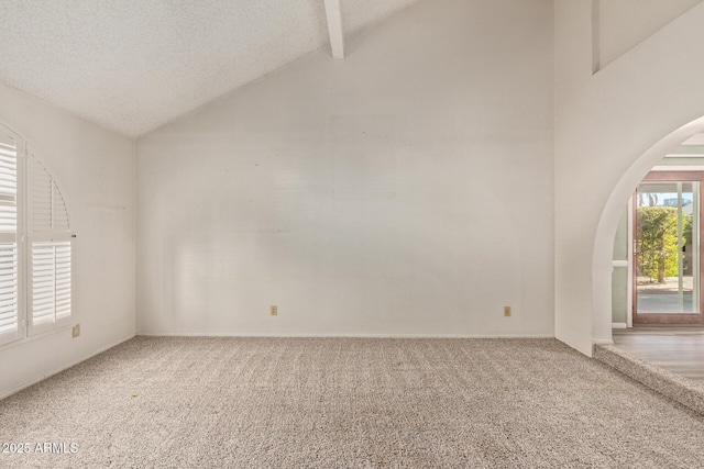 carpeted spare room with a textured ceiling and vaulted ceiling with beams