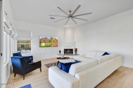 living room with a large fireplace, light hardwood / wood-style floors, and ceiling fan