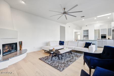 living room featuring light hardwood / wood-style flooring, a large fireplace, and ceiling fan