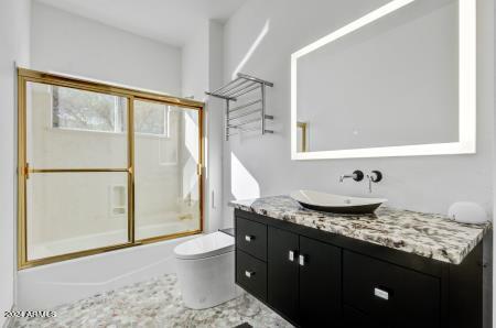 full bathroom with enclosed tub / shower combo, vanity, and toilet