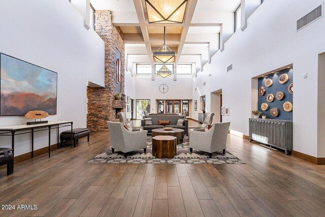 living room with a fireplace, a towering ceiling, and dark hardwood / wood-style flooring