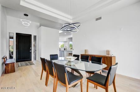 dining room with a notable chandelier, light hardwood / wood-style flooring, and a raised ceiling