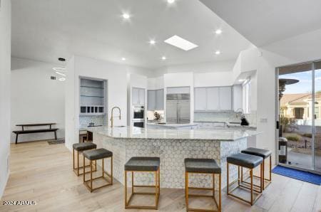 kitchen featuring a large island, stainless steel appliances, light wood-type flooring, and white cabinetry