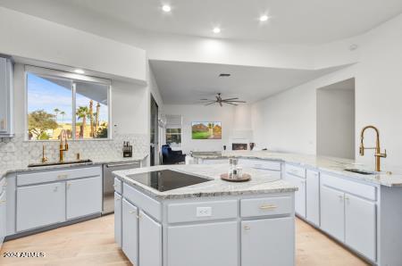 kitchen with decorative backsplash, stainless steel dishwasher, a kitchen island, and sink