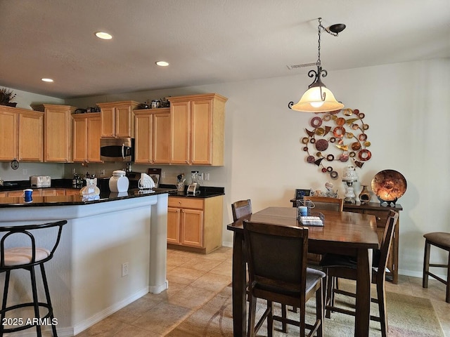 kitchen with dark countertops, baseboards, recessed lighting, stainless steel microwave, and decorative light fixtures