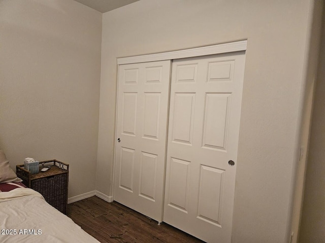 bedroom with baseboards, dark wood finished floors, and a closet