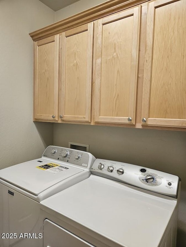 laundry room with washing machine and clothes dryer and cabinet space